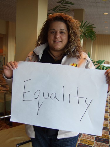 photo of Tamara Weber holding a sign reading "Equality"