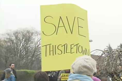 woman holding a sign saying SAVE Thistletown