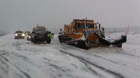 photo of a snowplow on the highway with other vehicles stopped